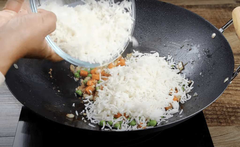 adding the rice to the wok